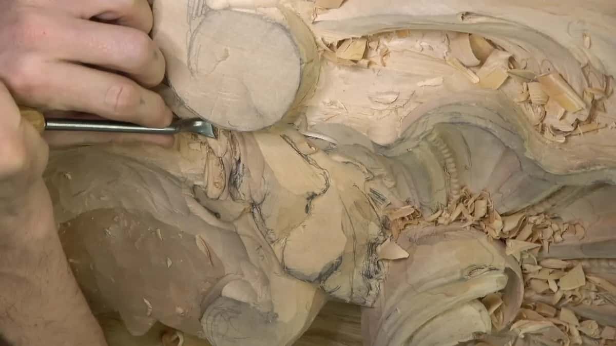 A long gouge comes in level from the left, a second hand resting at the top edge.