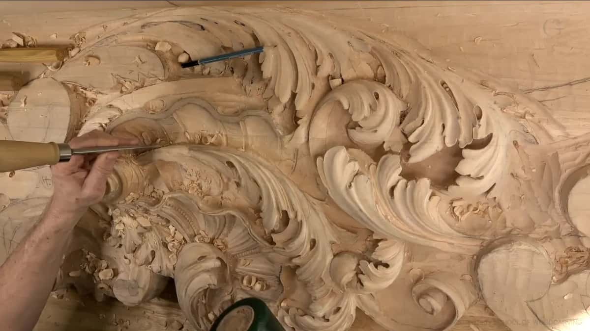 A long pale handle held nearly flat, its blade pushing along the edge.