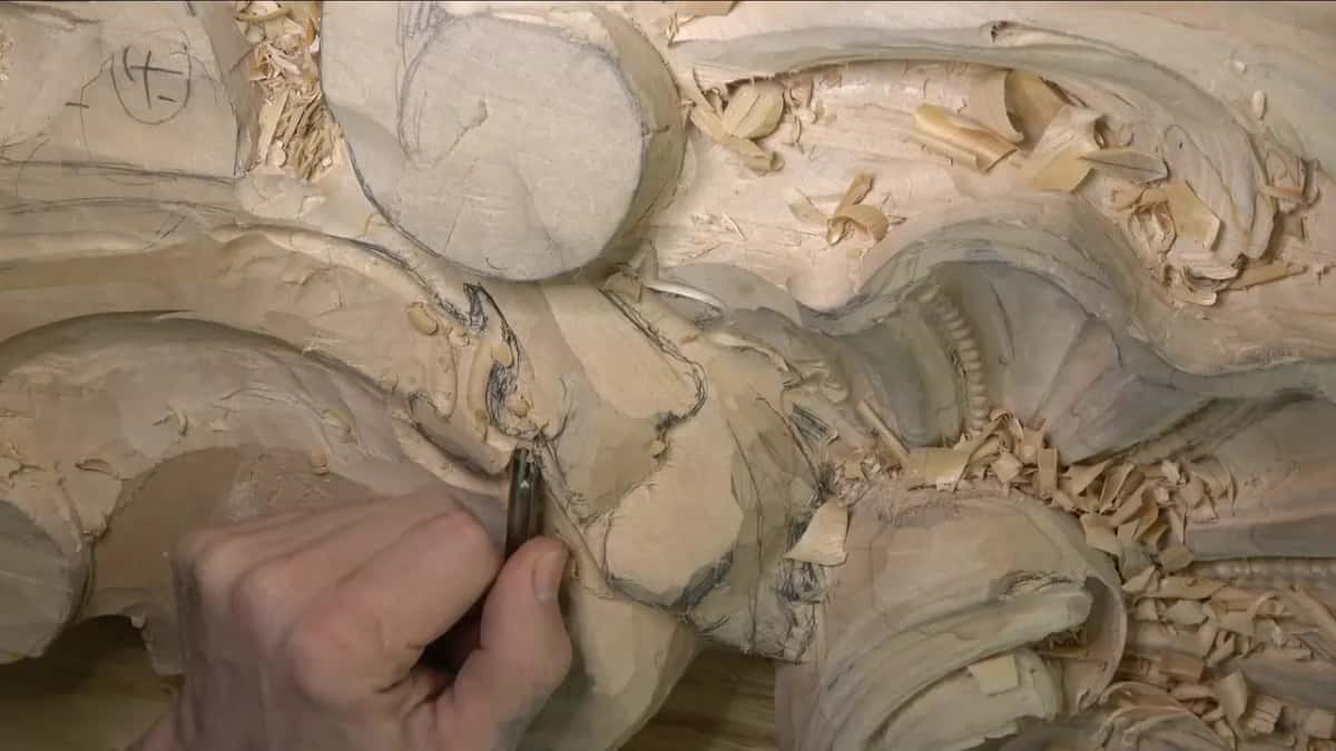 Low grip on a slim blade, the fingertips nearly on the wood.