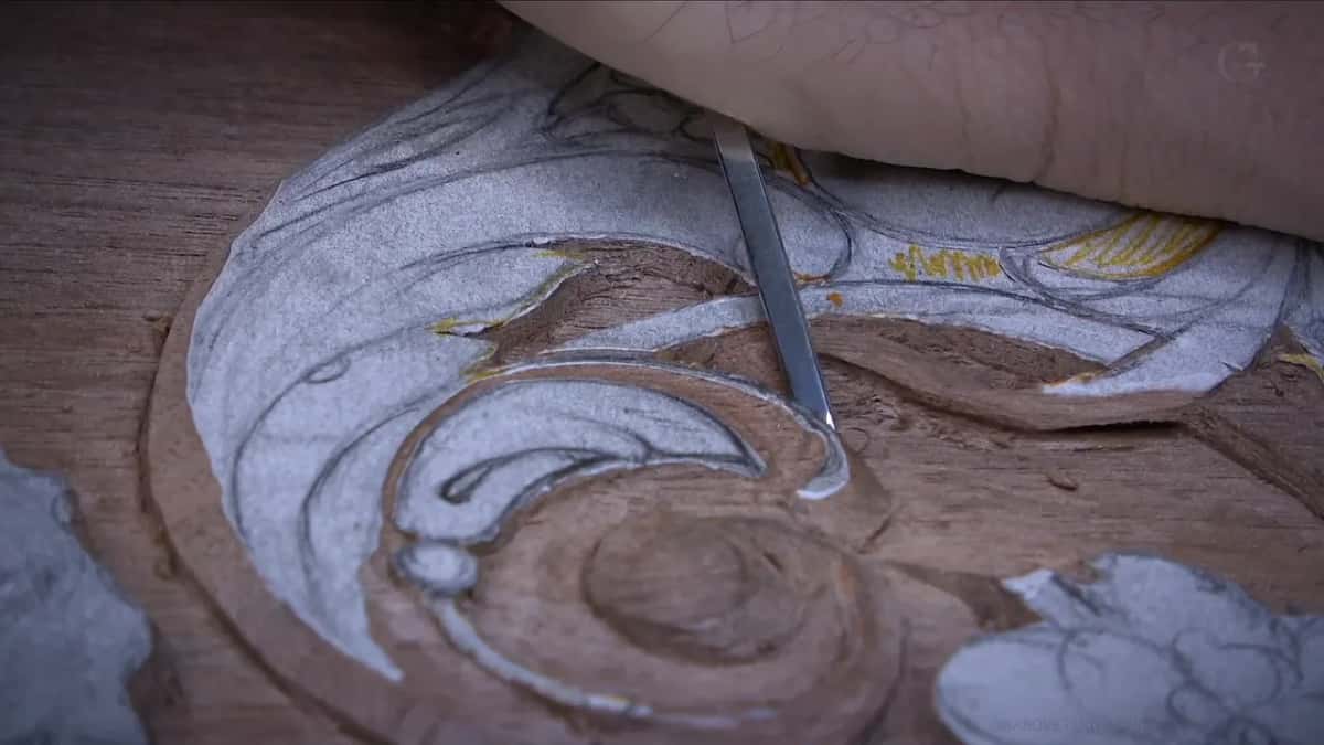 Forearm above the volute, tool angled into the drawn swirl