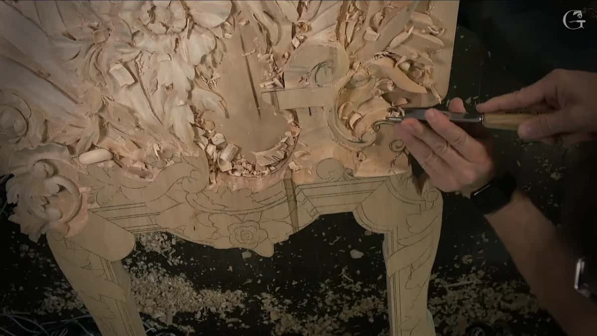 Gouge held level at the lower edge of the carving, both hands on it
