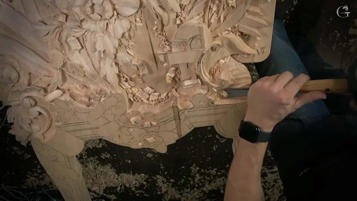 His right hand drives a long gouge through the waste near the molding