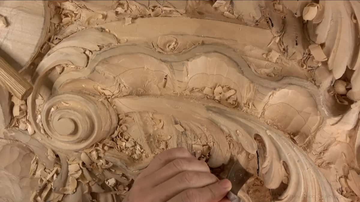 Mallet handle poking in at the top left, and one hand steering a gouge through the hollow.