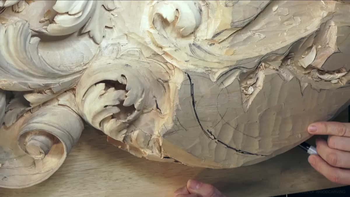 A black marker line curves down the rough, faceted chunk, a finished scroll just to its left.