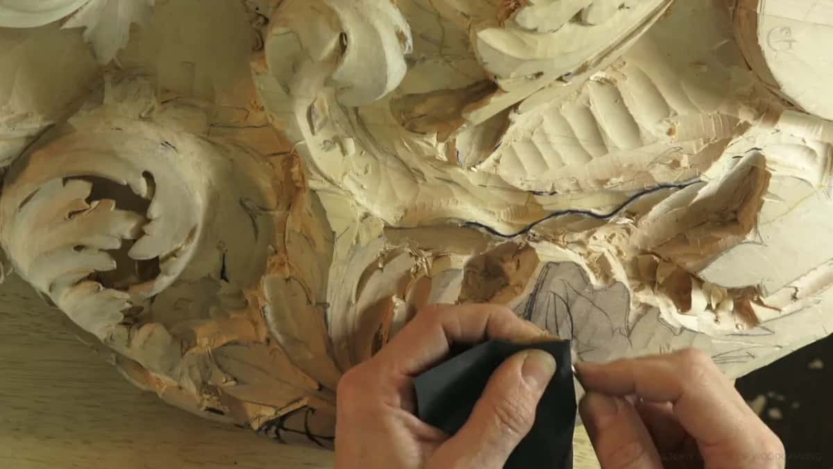 Folded paper pinched between finger and thumb while the small tool is worked against its face.