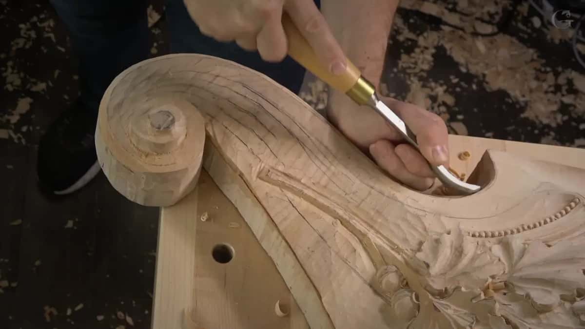 Brass ferrule and a long handle, the wide gouge digging inside the scroll's tight inner curve.
