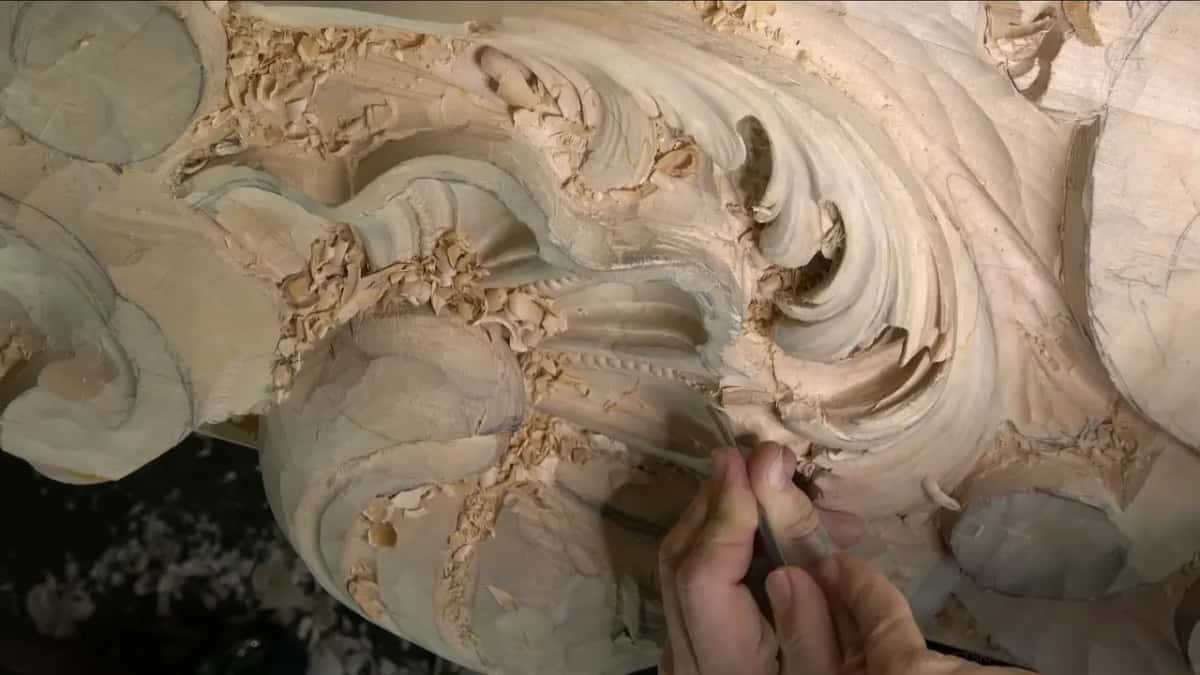 Narrow blade on the shell edge, two hands on it, shavings over the beaded rows behind.
