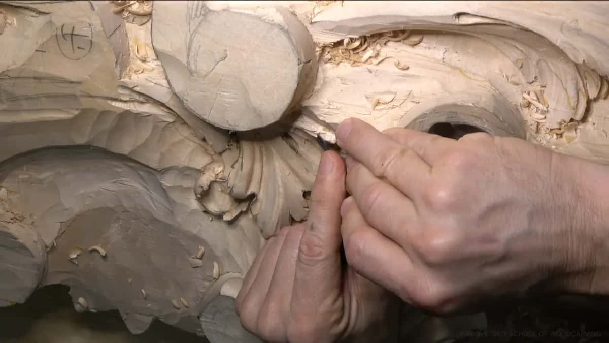 Held in both hands, a narrow tool carves a small concave in one lobe.