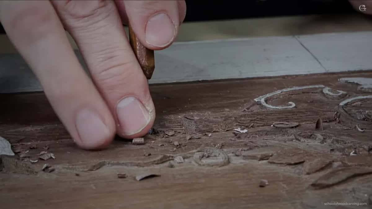 Fingers braced flat on the board with the tool resting across them, which turns the whole hand into a spring.