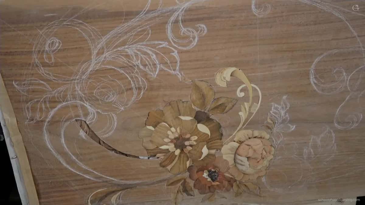 A marquetry panel laid flat, a flower built from different woods with the rest of the design still drawn on.