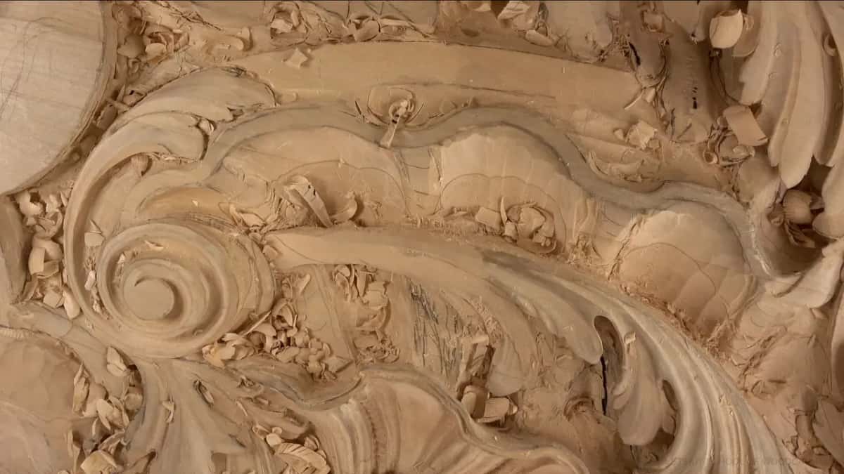 The volute and the shell Close on a carved spiral with a fan shaped shell above it and fresh chips loose in every hollow