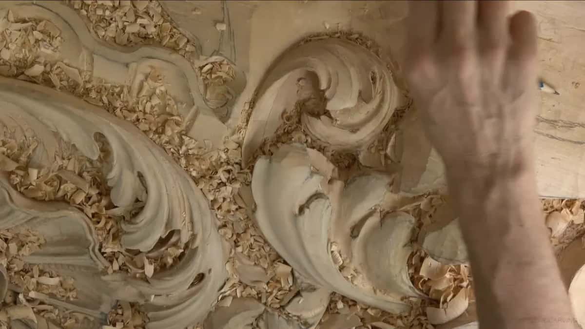 Buried in shavings Two acanthus leaves half buried in loose shavings, his hand sweeping into frame at speed in motion blur