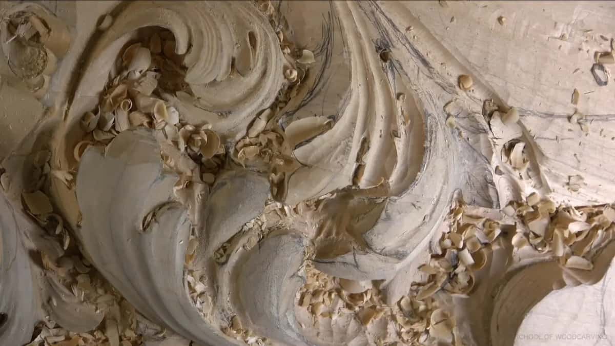 Where the light stops Dark shadow pockets sitting under the carved lobes, pencil lines still on the wood and shavings in every hollow