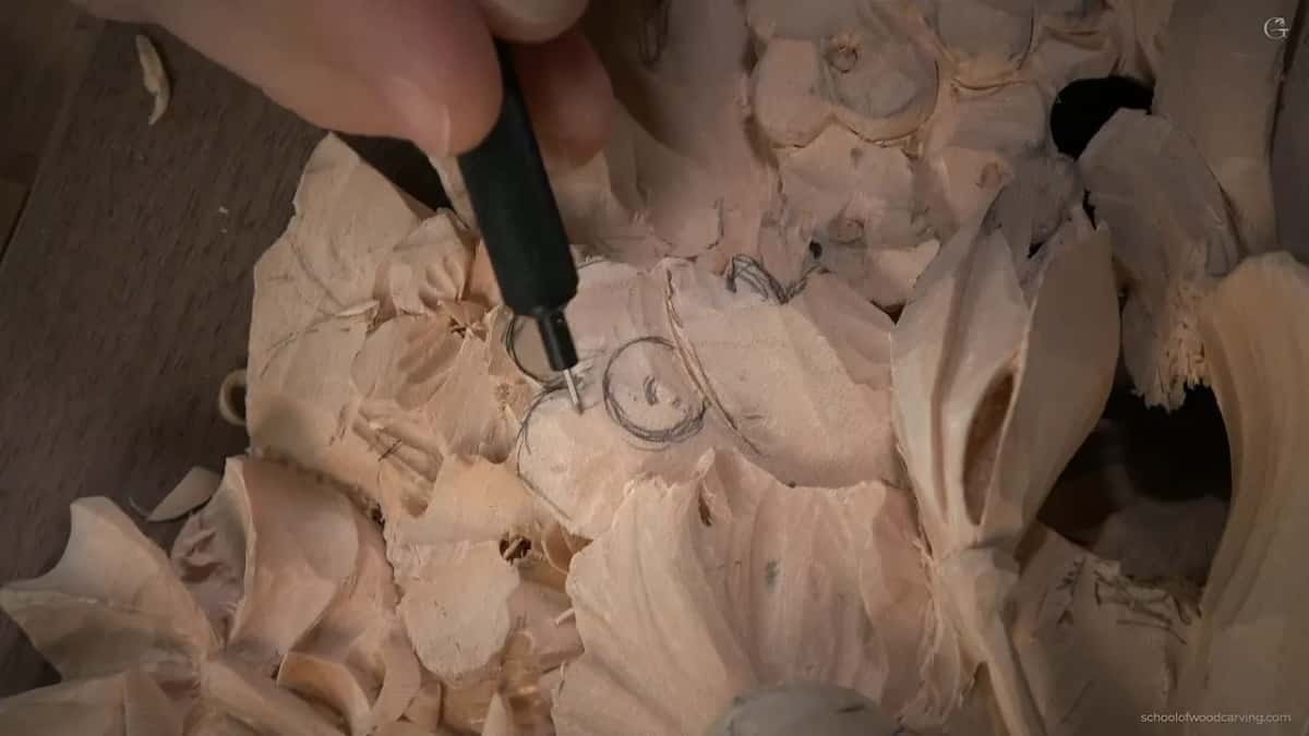 Carving a different flower beneath the parsley leaf, the tool at a small round center with almost no wood left behind it