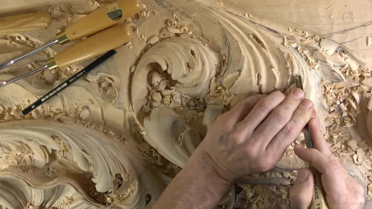 Pencil lying above, two hands carving below it.