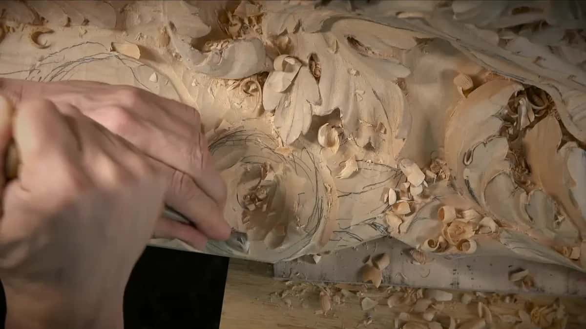 Pencil circles mark where the flower sockets go, and a hand works a gouge inside one