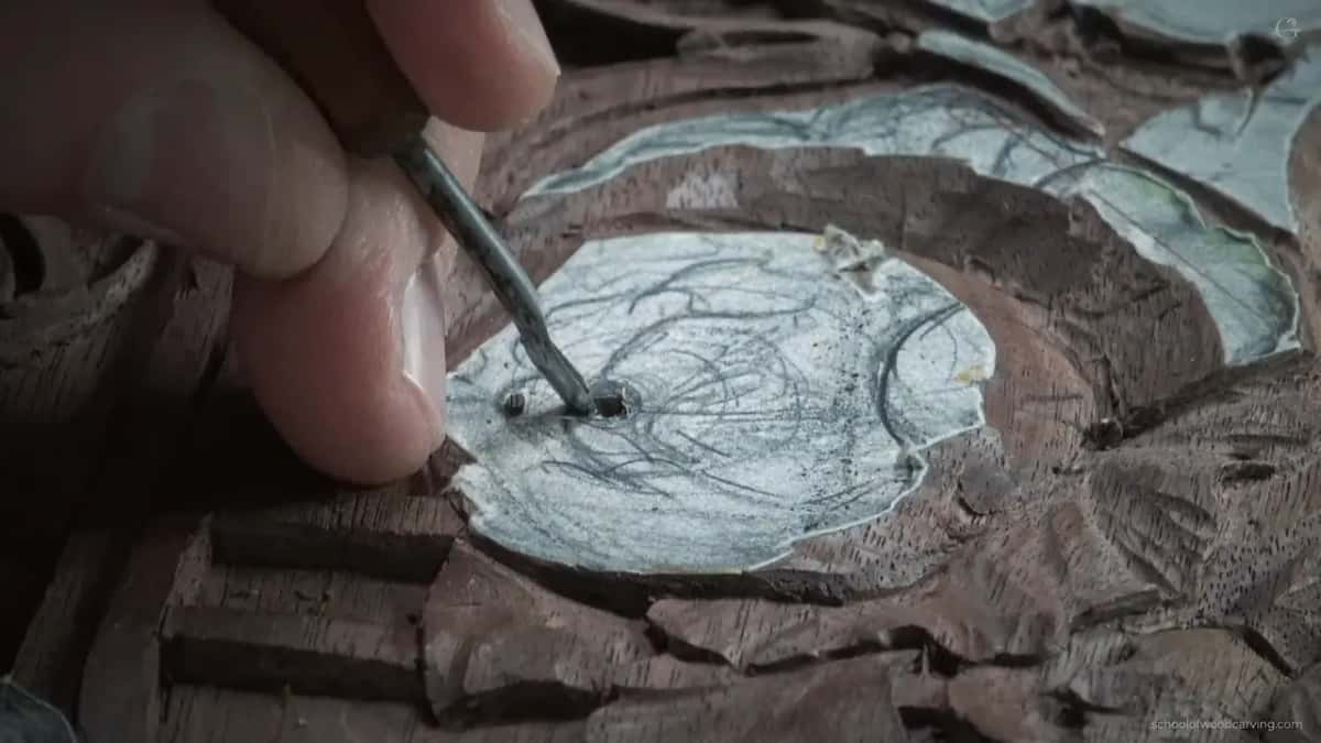 Two fingertips pinch the small gouge upright.