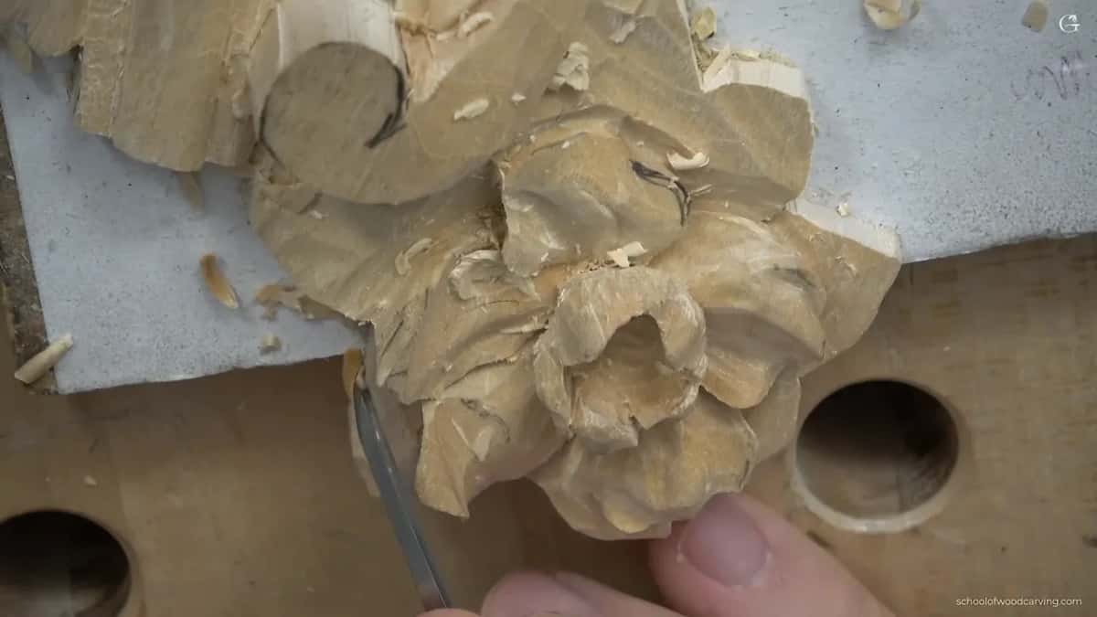 Thumb braced on the work while a knife begins the roll right at a petal end.