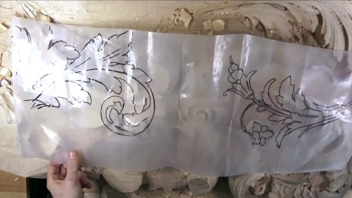 A sheet of clear plastic held over the board, with marker drawings of two acanthus scrolls and a spray of flowers.