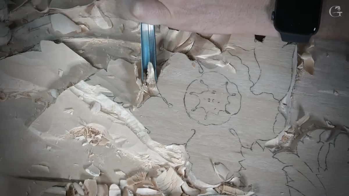 A narrow gouge stands in the groove at the edge of a flower still drawn in pencil