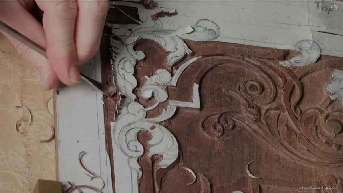 Dark handled tool working the corner scroll.