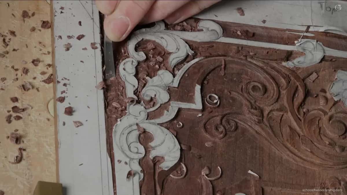 Dark tool clearing background, chips piling up beside the scroll where the pattern still sits.