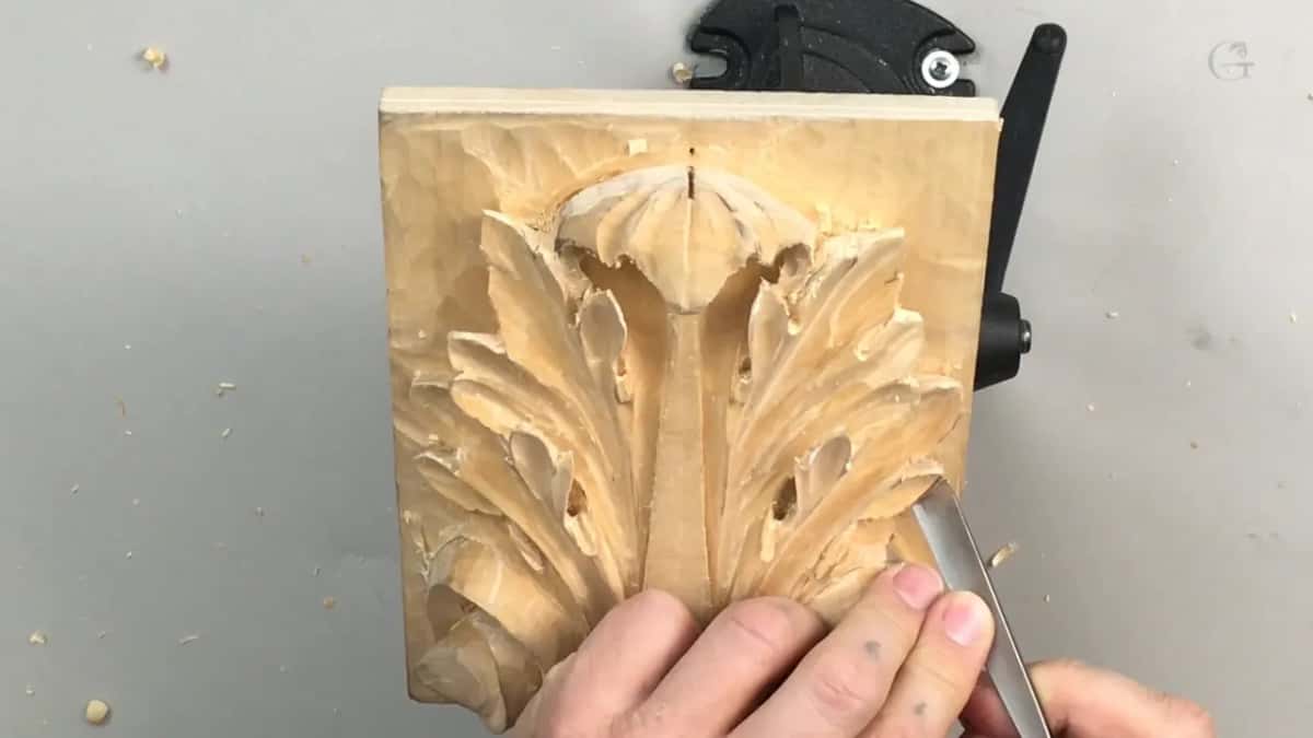 Panel standing upright with both hands low against it and a slim steel tool between the fingers