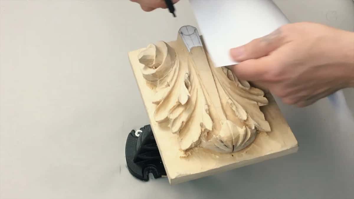 White sheet of paper held flat against the carving to carry a measurement across to the matching side