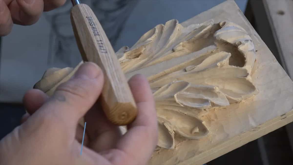 Pale ash handle held upright so the camera can see the whole tool, panel out of focus behind