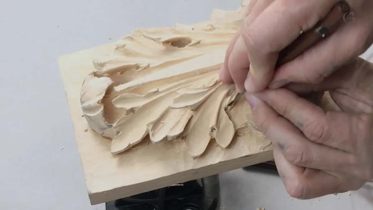 Fingers pinched high on the tipped board, blade so short it barely shows past the knuckles