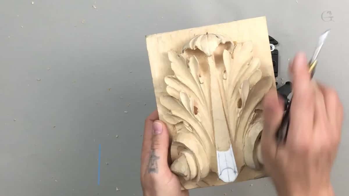 Dark tool arriving at the right edge, the other hand flat against the board to steady it