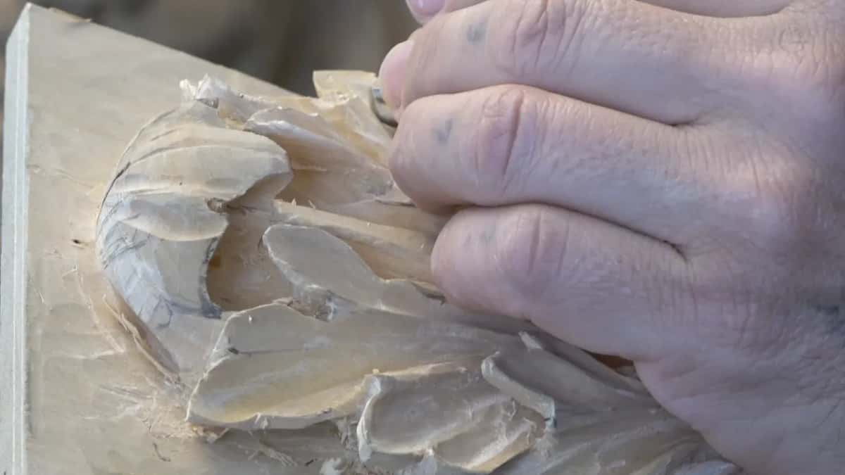 Knuckles large in frame, right over the carving