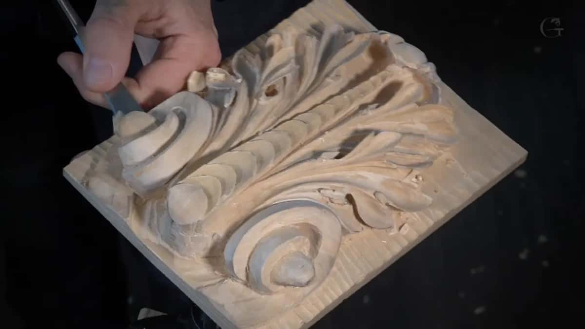 Flat chisel laid along the top edge of the panel, squaring the little step at the end