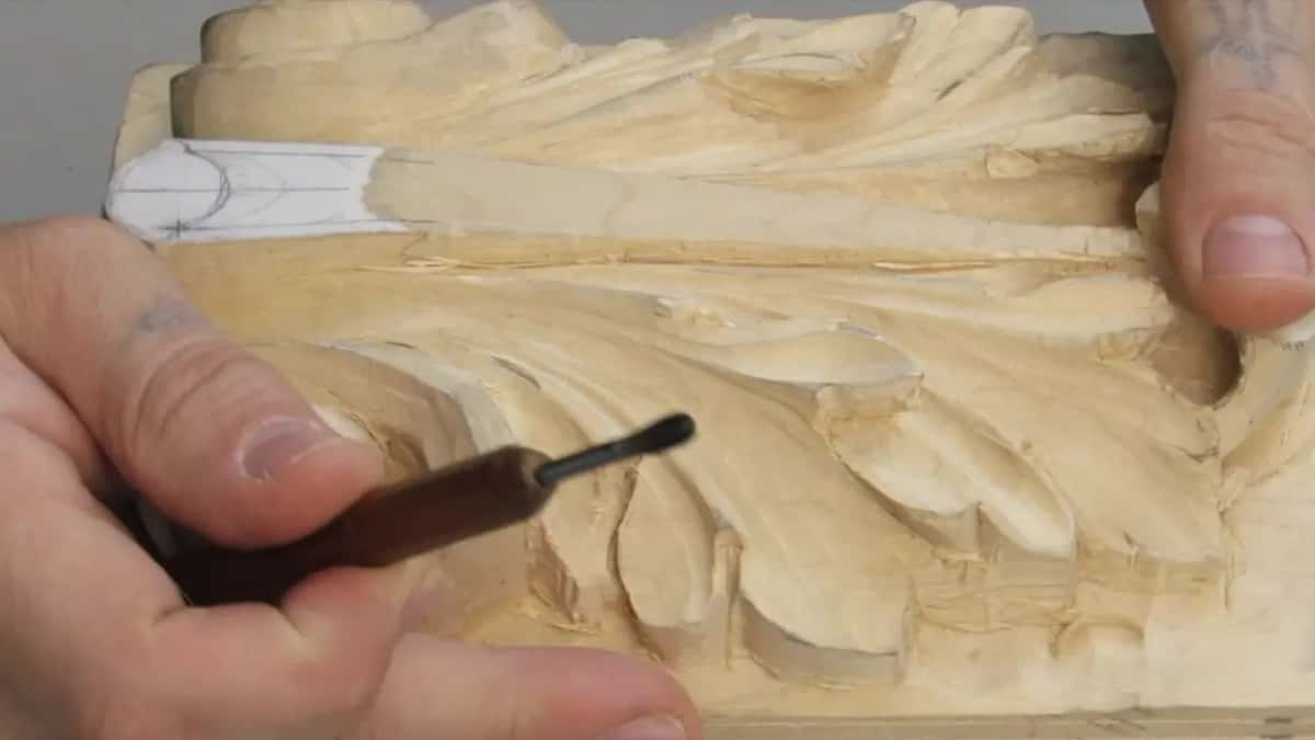 Slim dark blade pinched between the fingers, cutting beside a tube