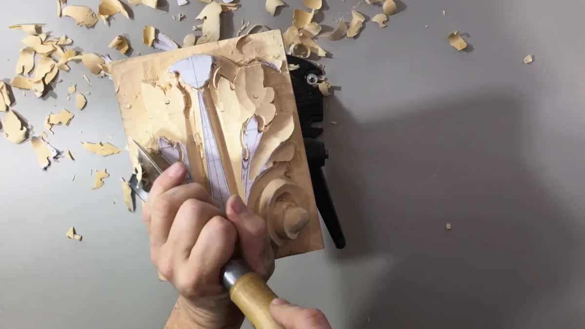 Two hands on a light handle at the leaf's left side, chips scattered over the bench