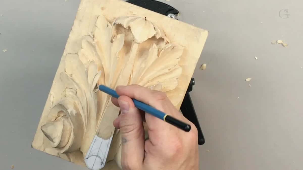 Blue pencil in his hand, drawing a line straight onto the carved surface