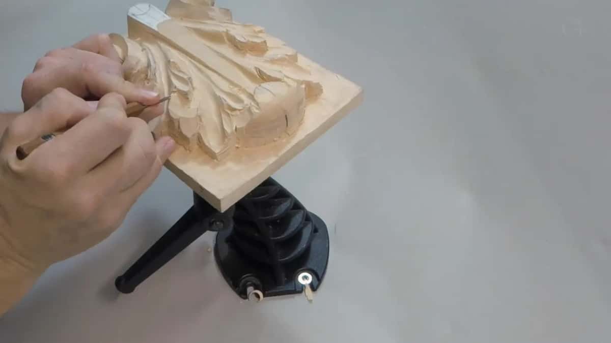 Steeply tilted board with both hands working the top left corner where the eye is being sunk