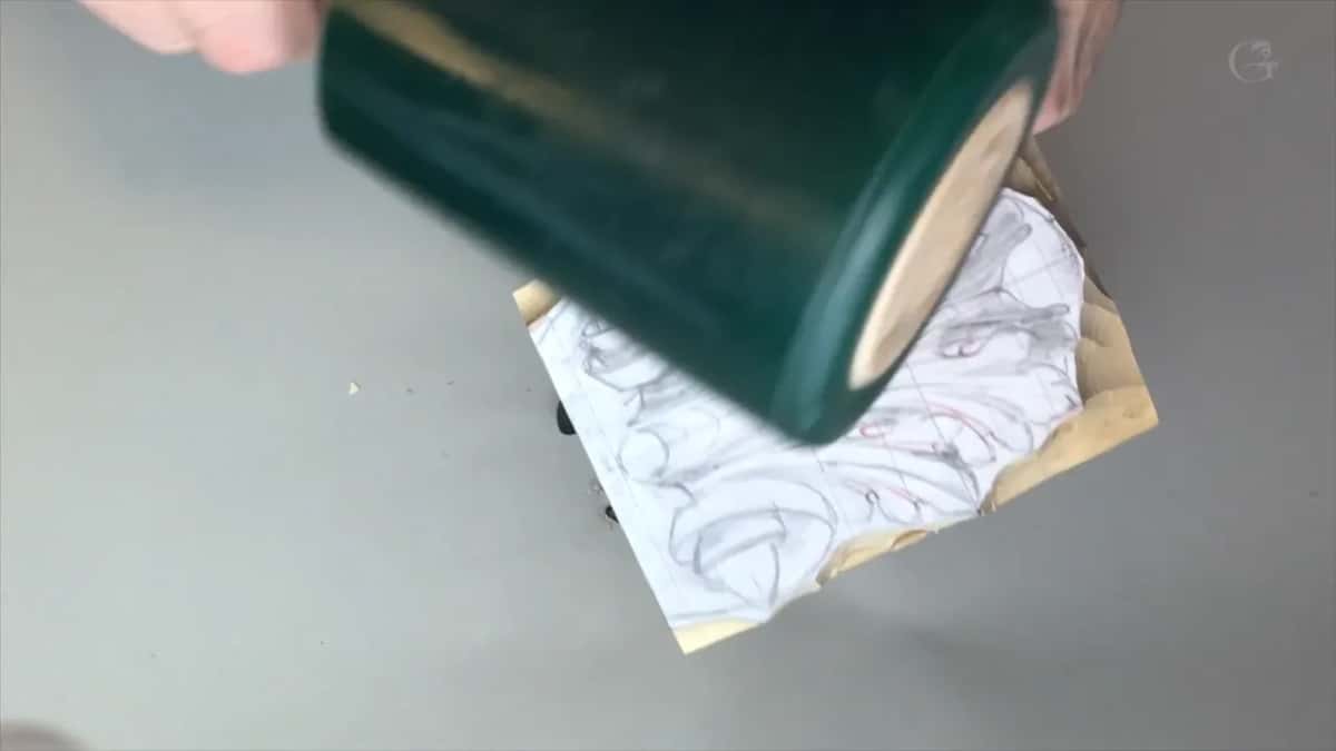 Mallet caught mid strike with its green head right over the carving