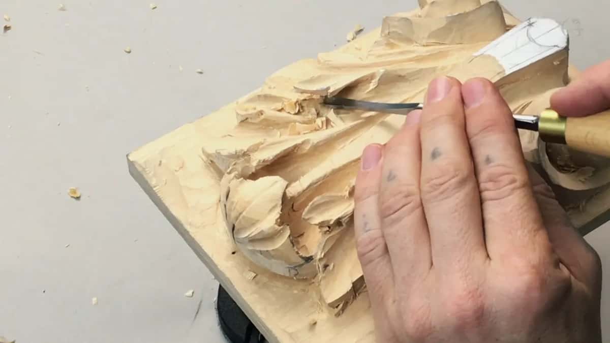 Hand spread across the carving, white tag up in the right corner