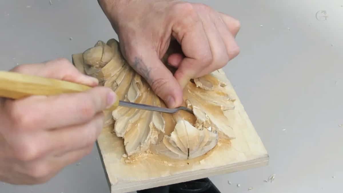 One finger pressing down partway along the shank, using it as a lever, the free hand gripping the board