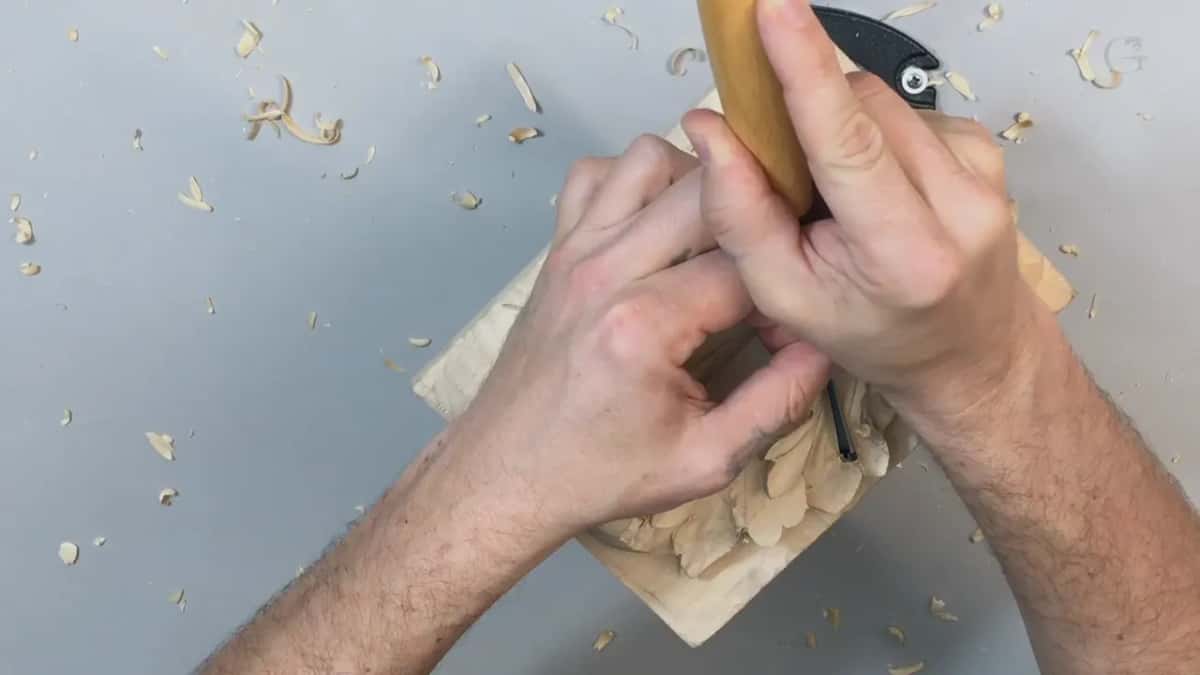 Gripped upright at the panel edge, a pale handle with the blade hidden behind the board