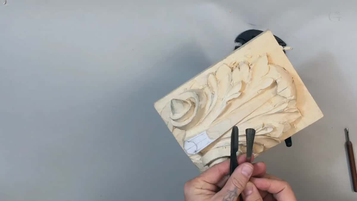 Two dark handled gouges held up side by side against the carving