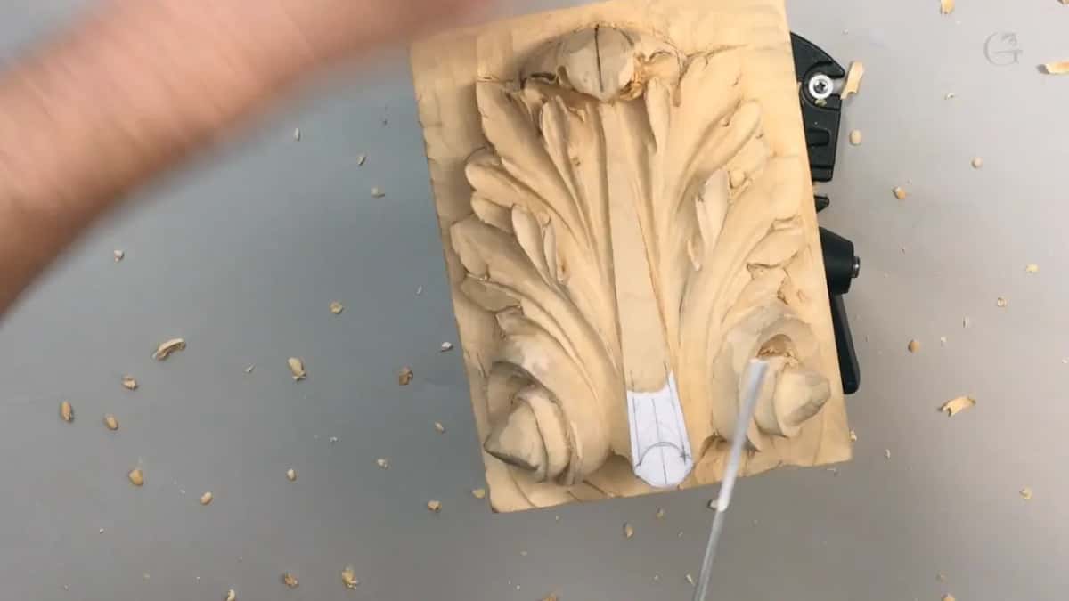 Panel upright on the vise, a hand blurred mid sweep, shavings everywhere on the grey table