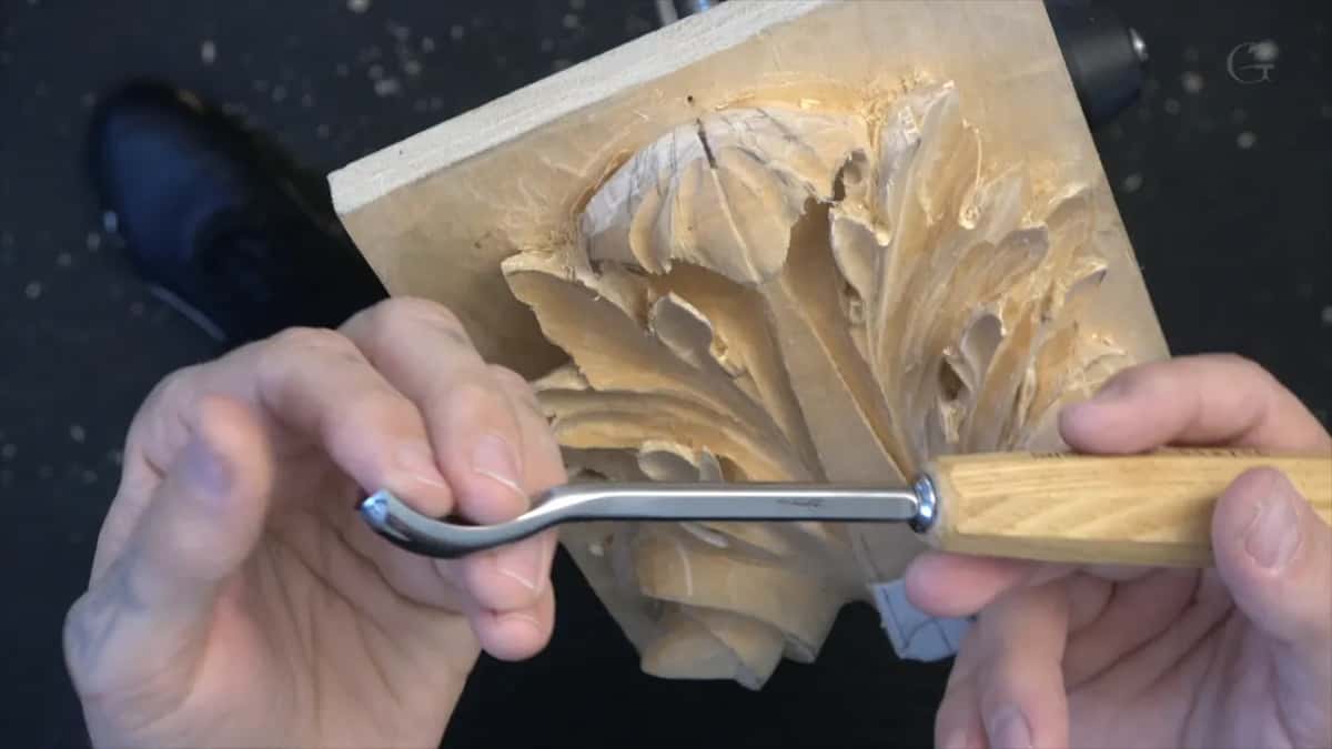Tool held out flat between both hands, pale handle toward the camera, panel waiting behind it