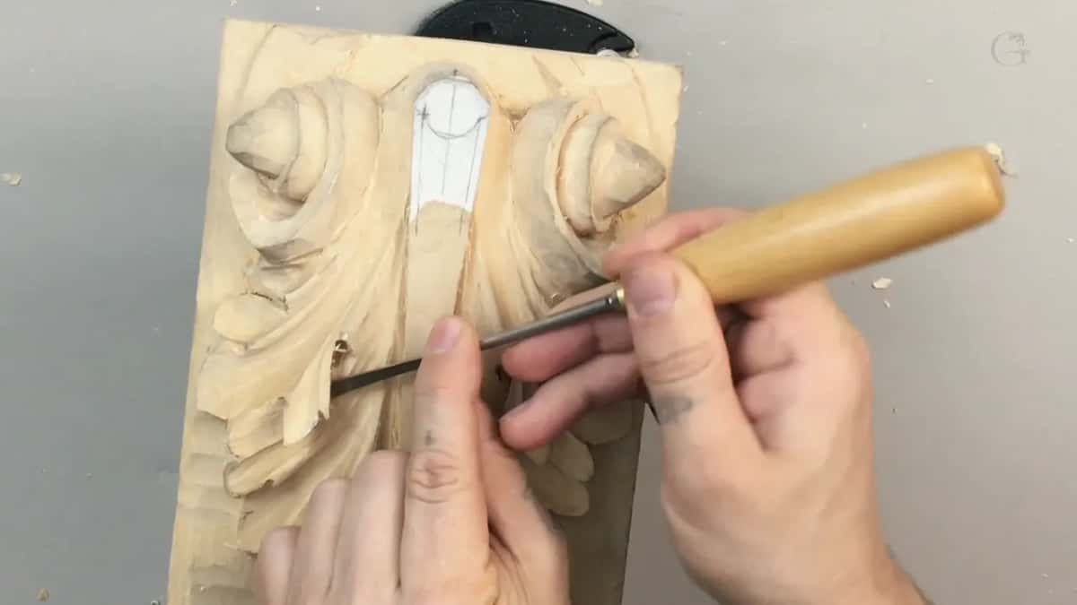 Pale handle gripped in both hands, blade down in the panel