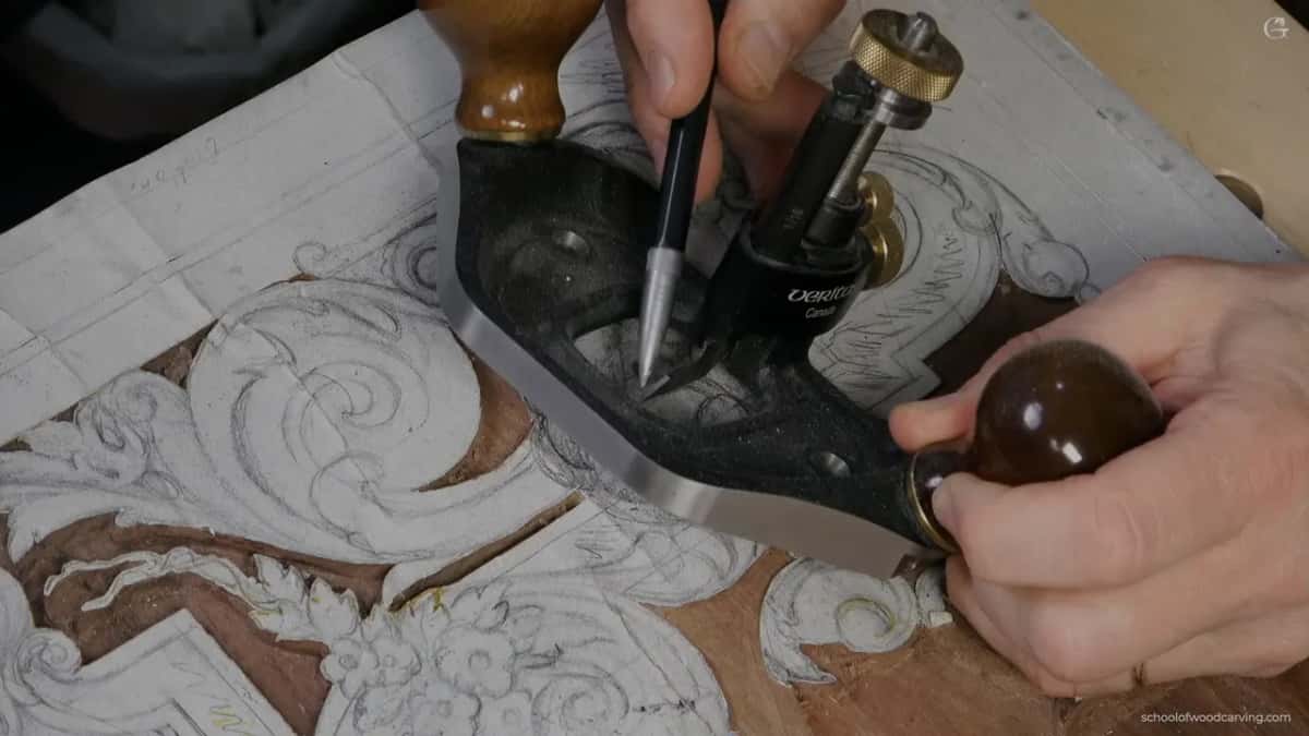 Cast iron router plane lying on the panel beside a pencil, brass depth screw standing up.