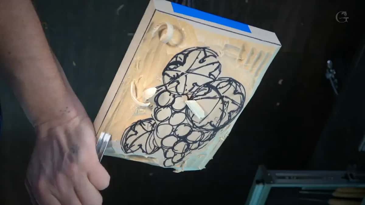 Grapes and leaves laid out in black marker before the first chip comes off the pale surface.