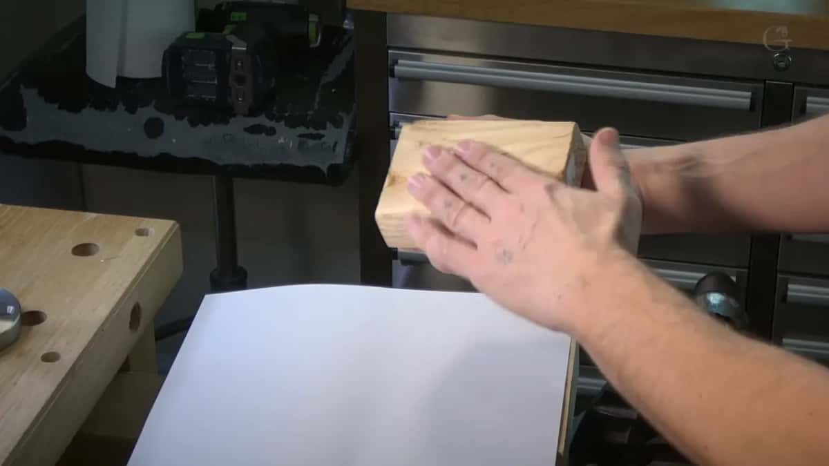 Scrap two by four held over a white sheet of paper.
