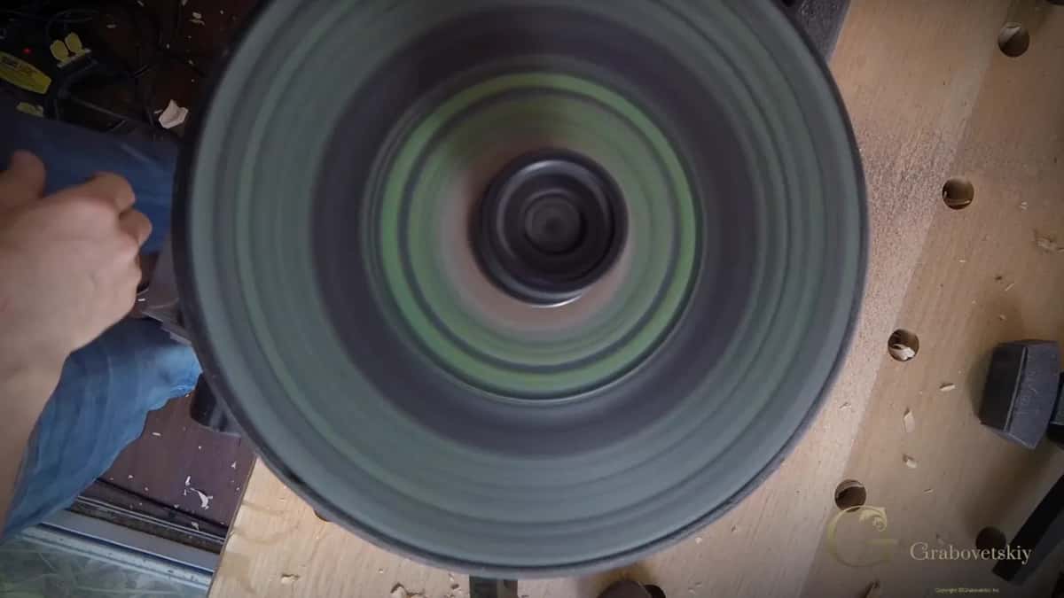 Bands of green compound blur into rings across the turning leather wheel.