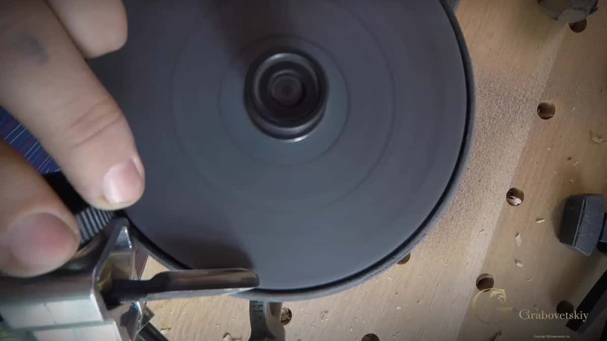 Fingers hold the clamp steady as the tool touches the dark face.